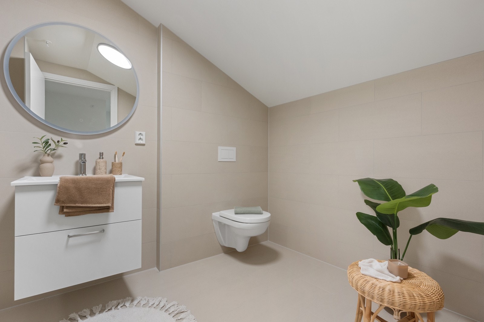 Badet har vegghengt toalett, servant med underskap, innglasset dusjhjørne og speil med belysning. Galleribilde