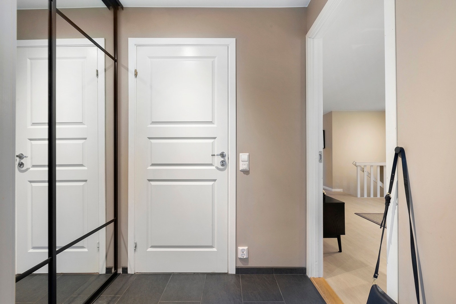 Entréen har praktiske fliser på gulv og en større skyvedørsgarderobe med god oppbevaringsplass til yttertøy og sko Galleribilde