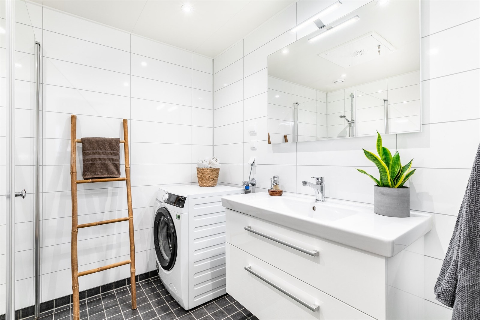 Badets gulv har fliser og varme, veggene er utført med flis-mønstrede våtromsplater. Galleribilde