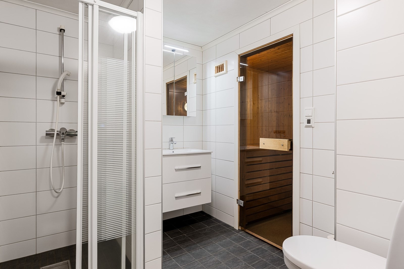 Flislagt baderom som ble rehabilitert i 2020 og innredet med dusjnisje, servant på innredning og toalett. Galleribilde