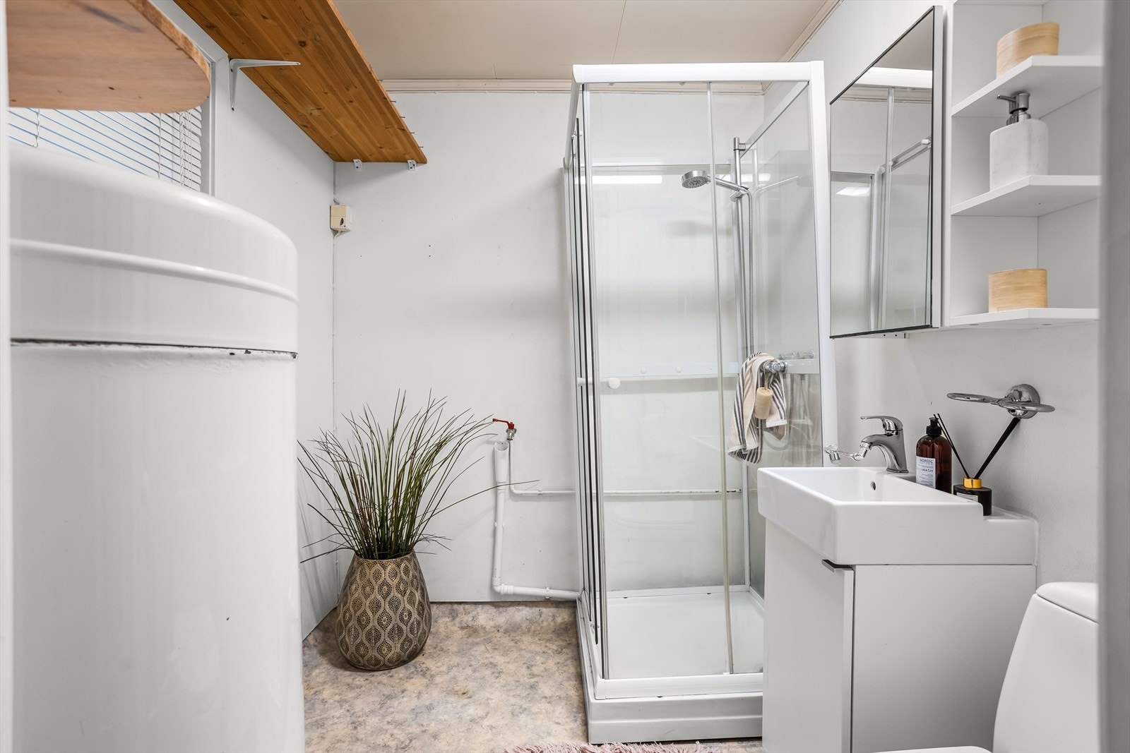 Funksjonelt, kombinert bad og vaskerom med dusjkabinett og opplegg for vaskemaskin. Galleribilde