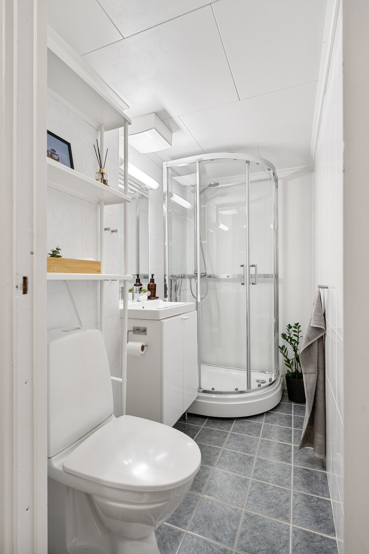 Lyst baderom med flis på gulvet og malte plater på vegger. Galleribilde