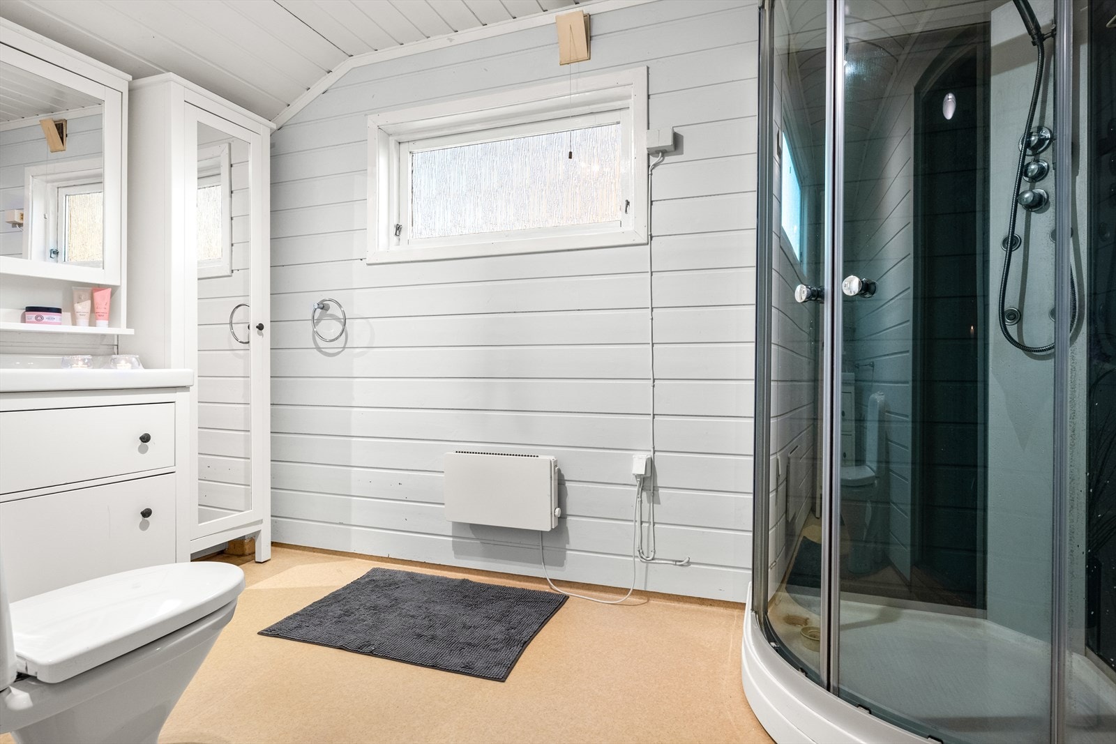 Badet er fra 90-tallet. Innredningen består av en servant med underskap, toalett og dusjkabinett. Galleribilde