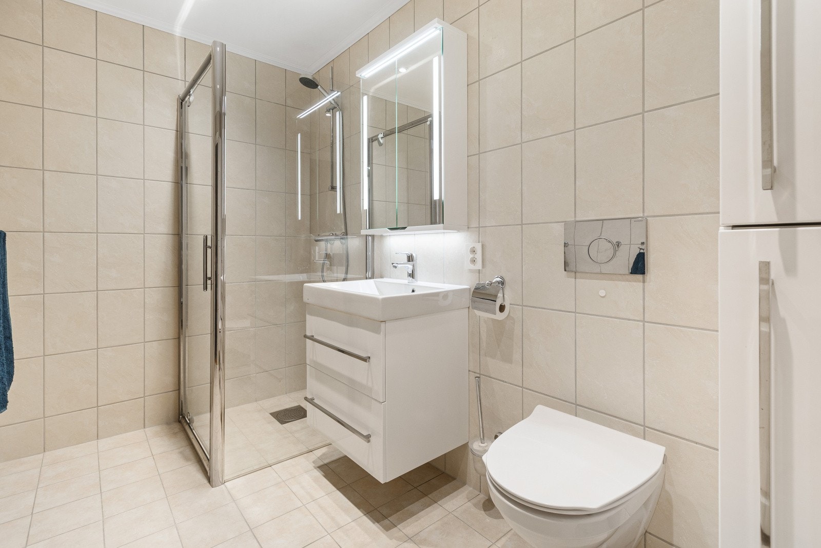 Pent flislagt baderom fra 2013 med vegghengt wc, dusjhjørne og baderomsinnredning. Galleribilde