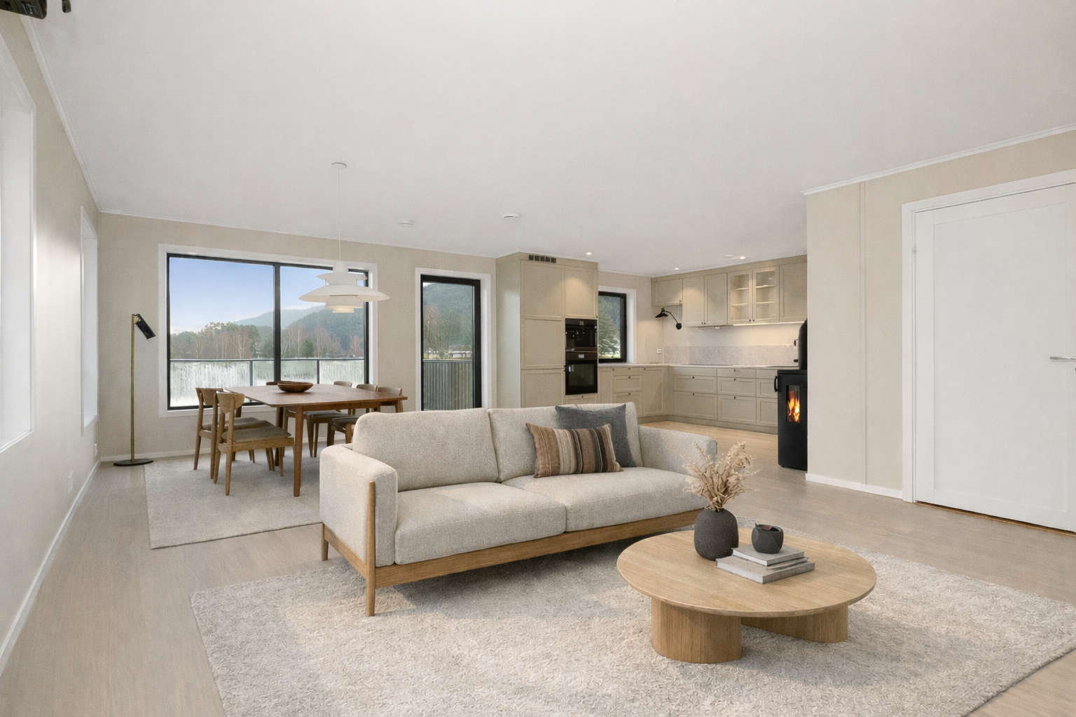 Stuen og kjøkkenet har en åpen løsning. Her er det lekkert gulv type Bjelin Woodura Planks og slette overflater på vegger malt i en delikat beige tone som er gjennomgående for store deler av boligen. Bildet er digitalt møblert og kun en illustrasjon. Galleribilde