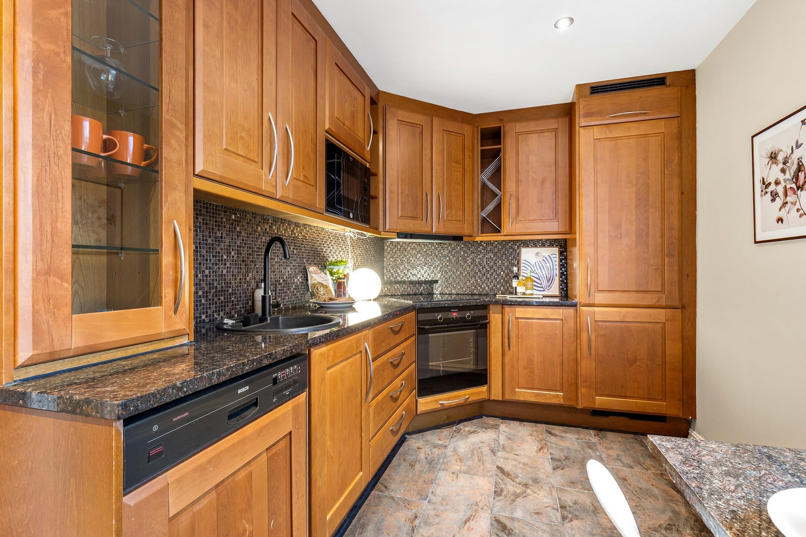 Kjøkkenet er innredet med profilerte fronter og benkeplate i stein. Benkeplaten har nedfelt vaskekum og praktiske fliser over benkeplaten. Galleribilde