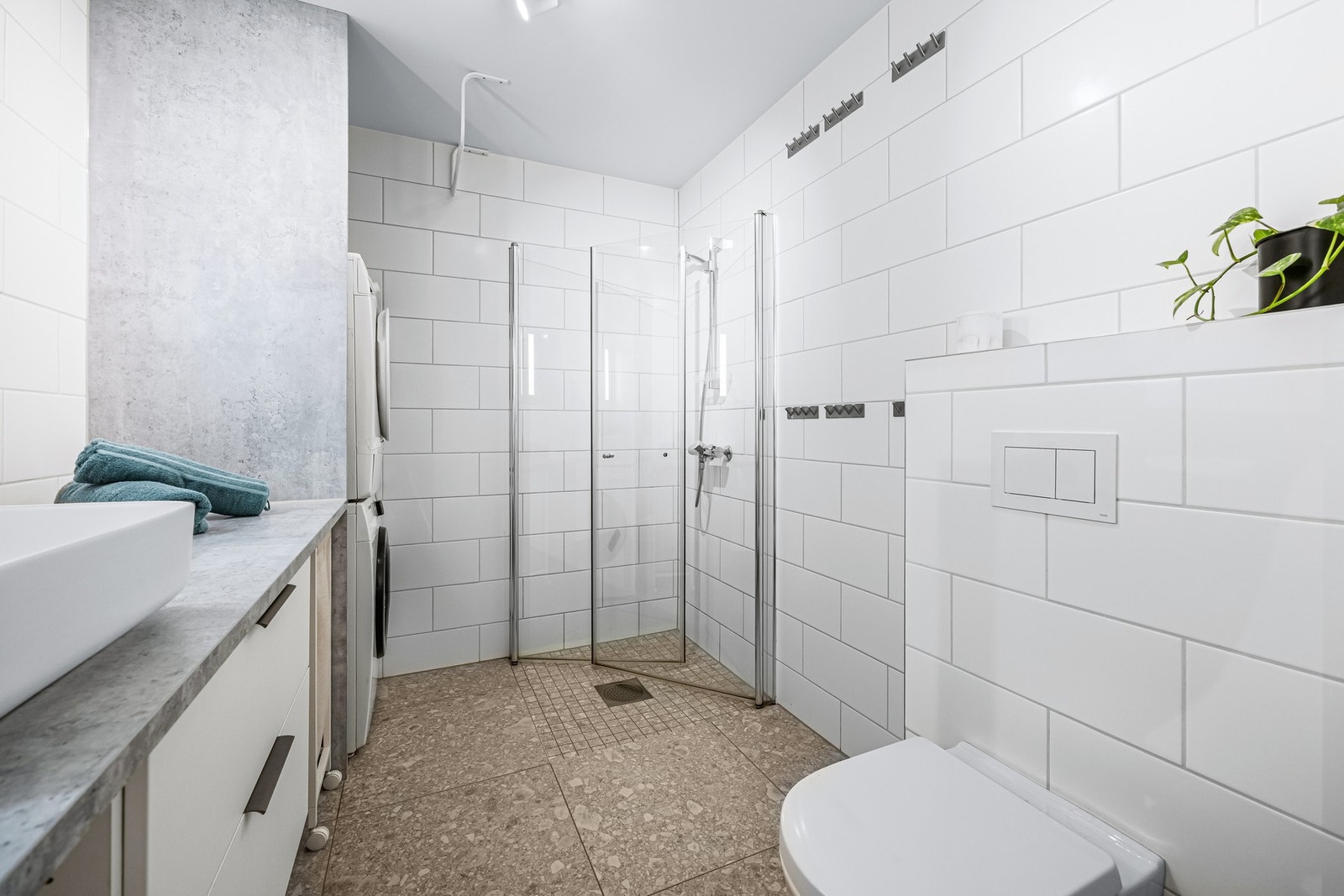 Videre har badet vegghengt toalett og dusjhjørne med innfellbare dører i herdet glass. Det er opplegg for vaskemaskin og tørketrommel i egen nisje. Galleribilde