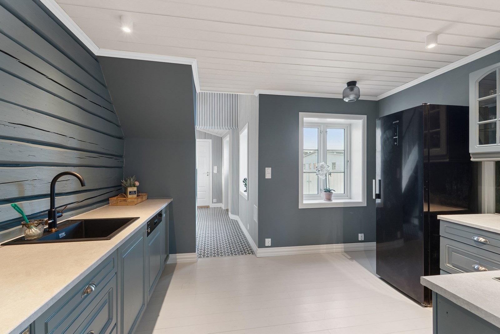 Rommet har heltrebord på gulvet, malte plater og en laftet vegg som gir karakter. Galleribilde