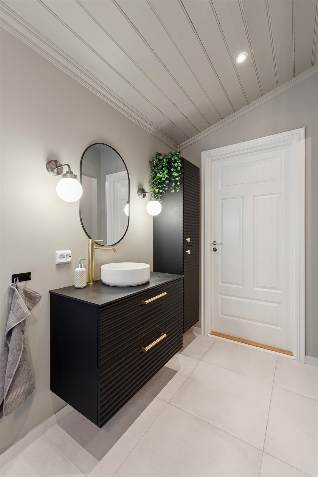 Badet er innredet med sort baderomsmøbel med heldekkende benkeplate og skålservant. Galleribilde