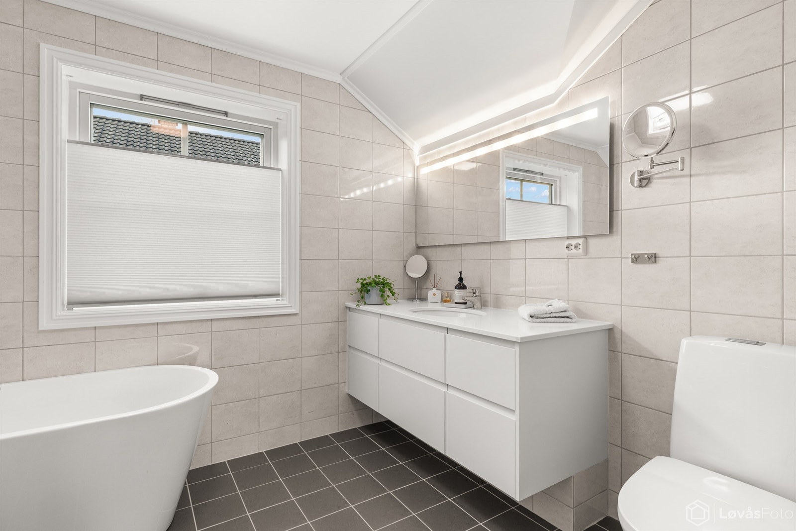 Baderomsinnredningen har vegghengt servantseksjon med skuffer og speil med integrert lys. Galleribilde