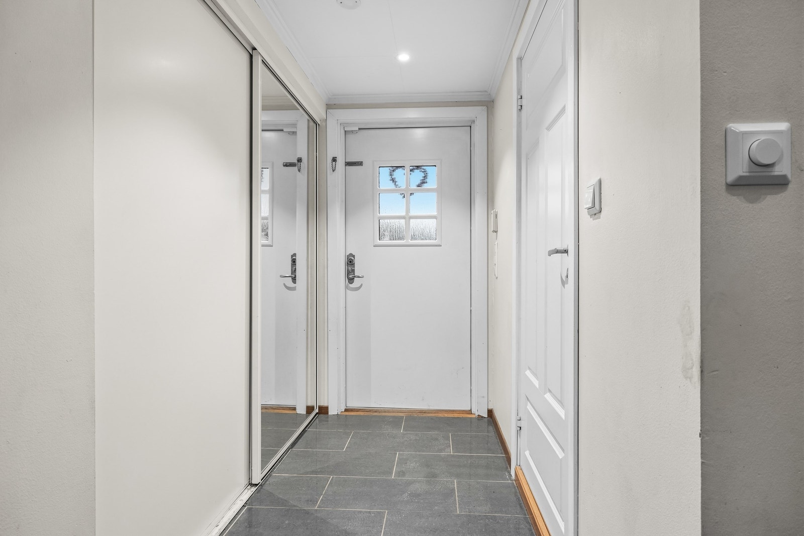 Innbydende entrè med flislagt gulv og skyvedørsgarderobe Galleribilde