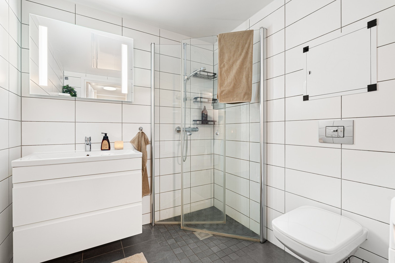 Innredning med nedfelt servant, veggmontert toalett, dusjvegger/hjørne og opplegg for vaskemaskin. Galleribilde