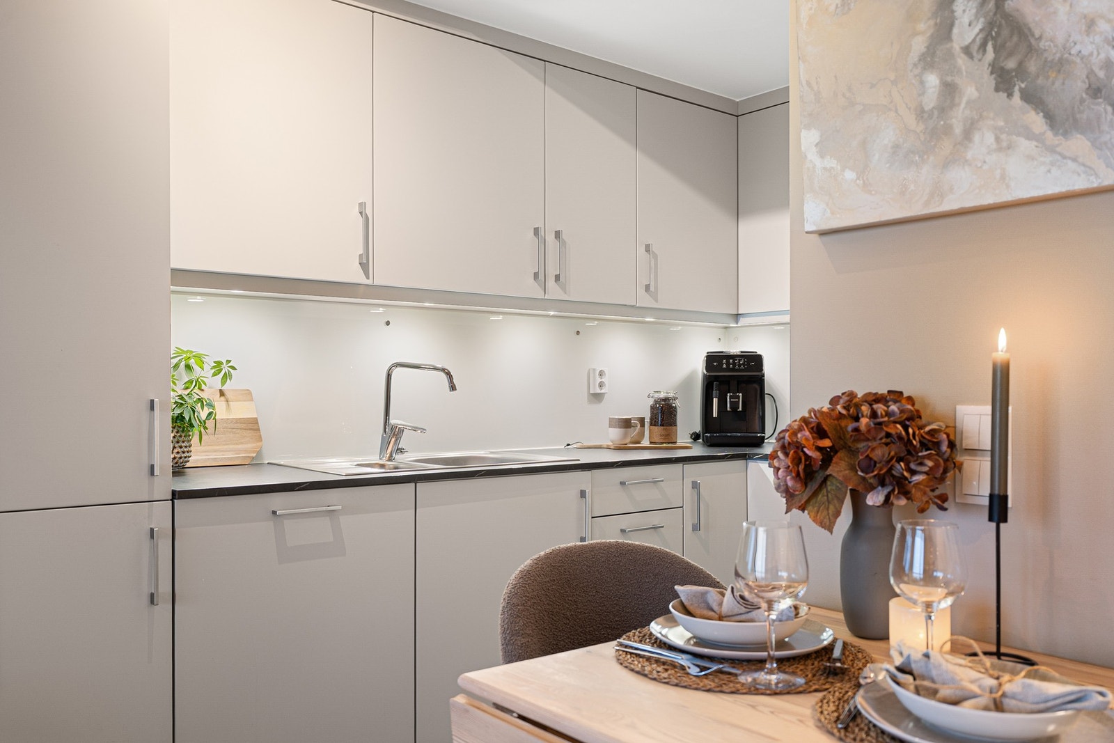 Lyst og klassisk kjøkken med glatte fronter og integrerte hvitevarer. Galleribilde