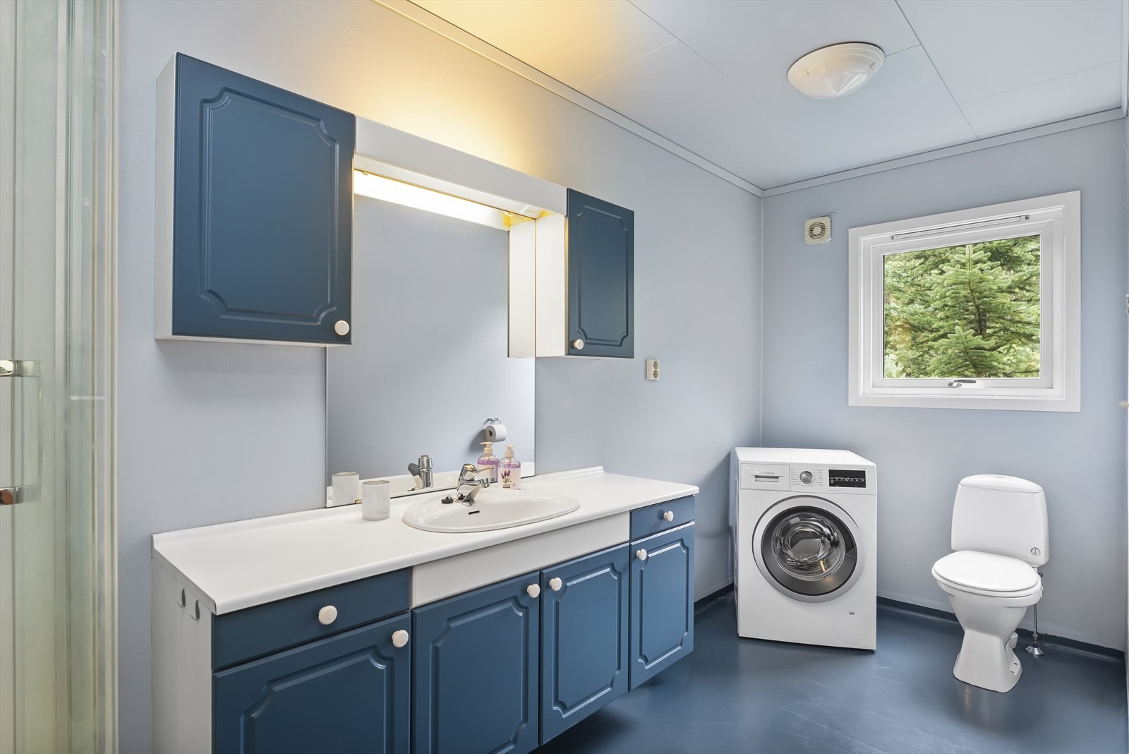 Bad med baderomsinnredning, toalett og dusjkabinett. Opplegg for vaskemaskin. Galleribilde