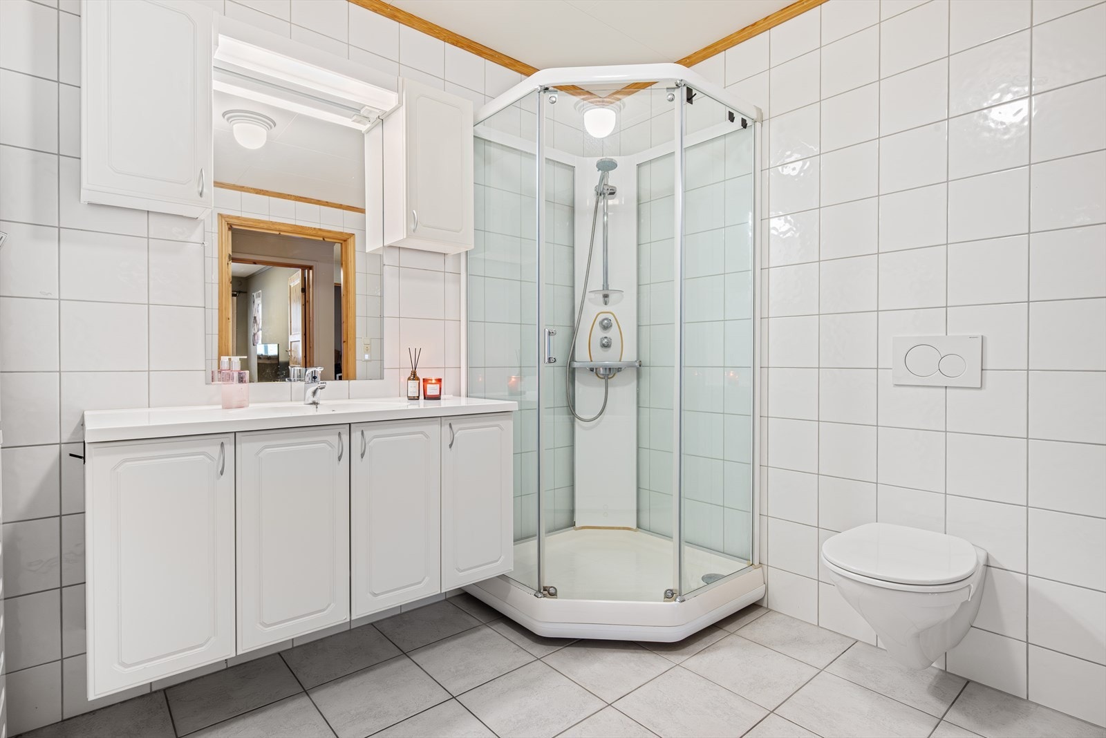 Badet har flislagte overflater, gulvvarme, dusjkabinett og badekar. Galleribilde