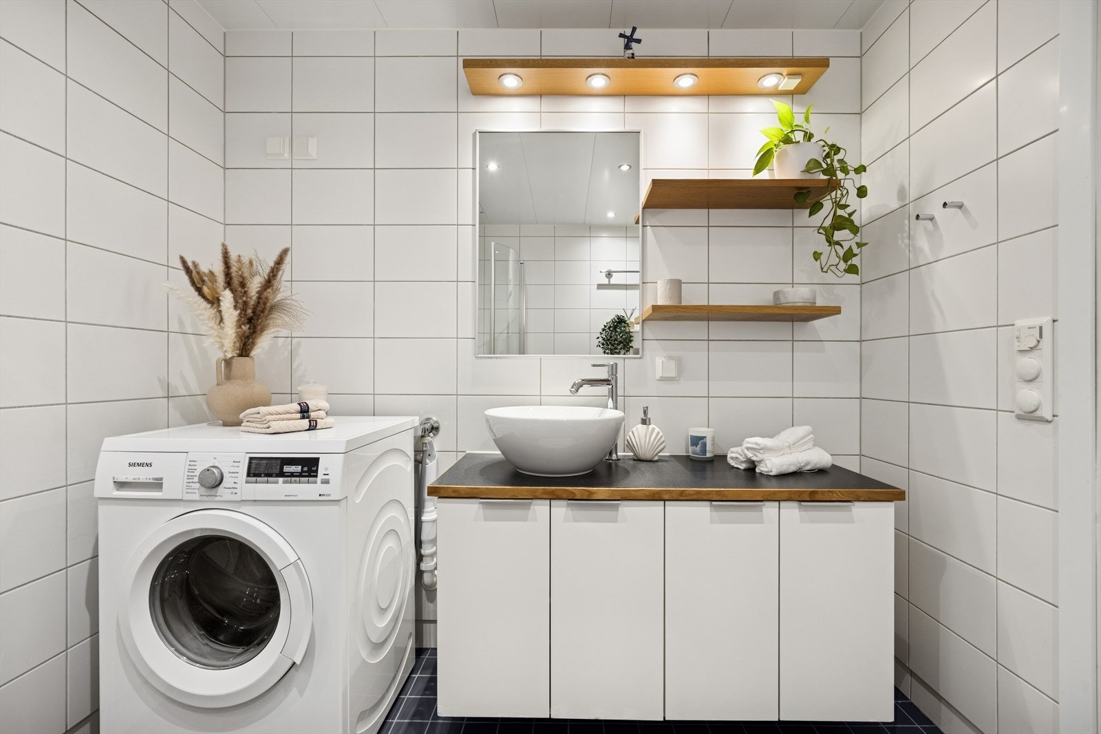 Praktisk baderomsinnredning med god benkeplass, skapplass og opplegg for vaskemaskin. Galleribilde