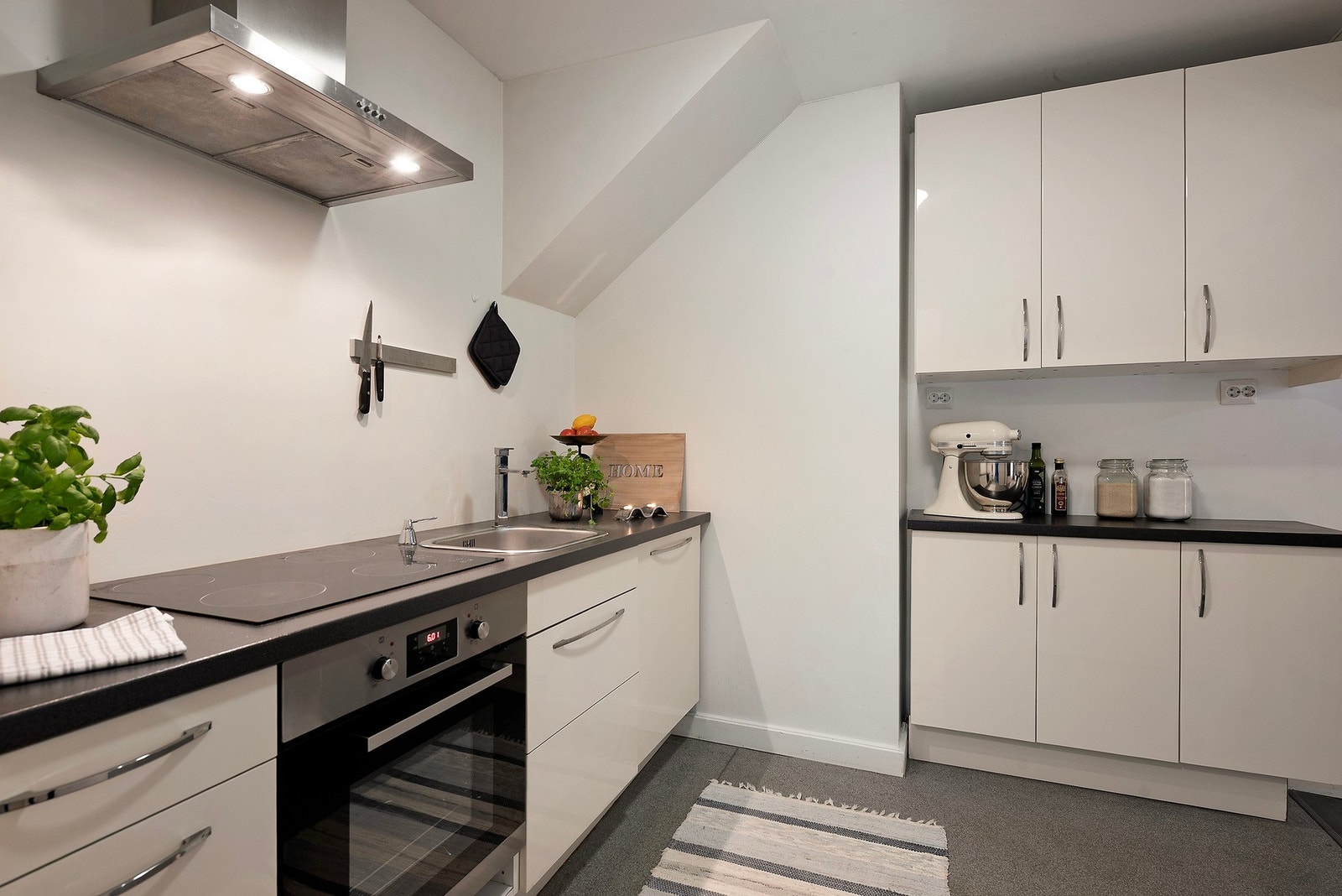 Kjøkkenet viderefører den lyse og nøytrale stilen, med integrerte hvitevarer og stilrene detaljer i børstet stål Galleribilde