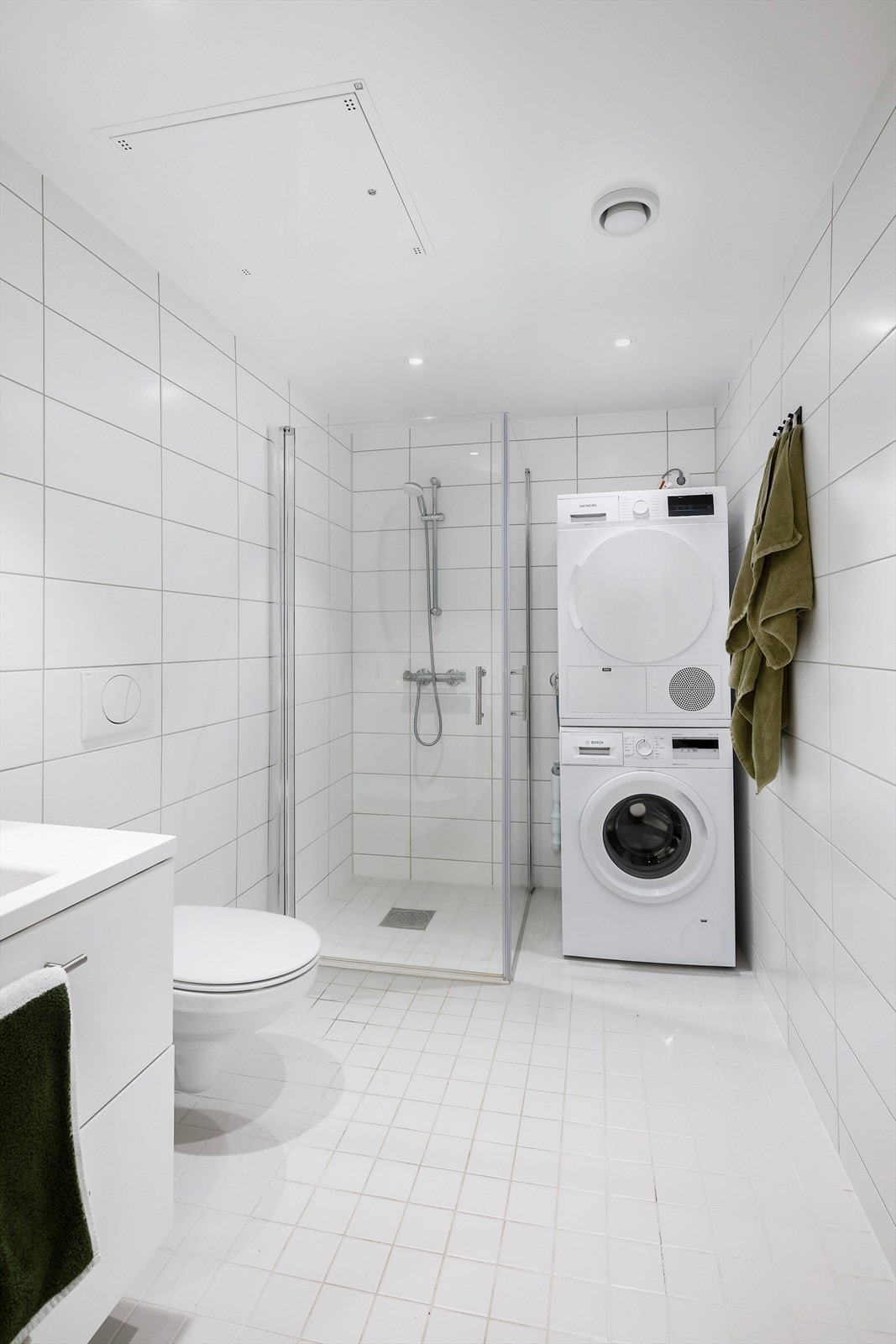 Lyst og moderne flislagt baderom med praktiske løsninger. Galleribilde