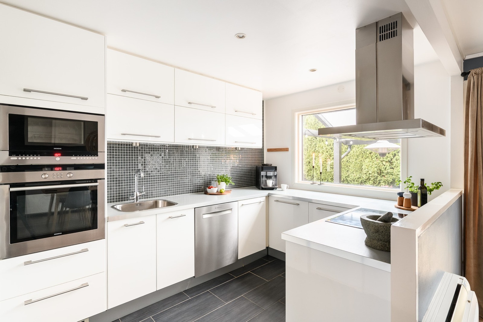 Kjøkkenet har en moderne utforming med lyse, glatte fronter. Galleribilde