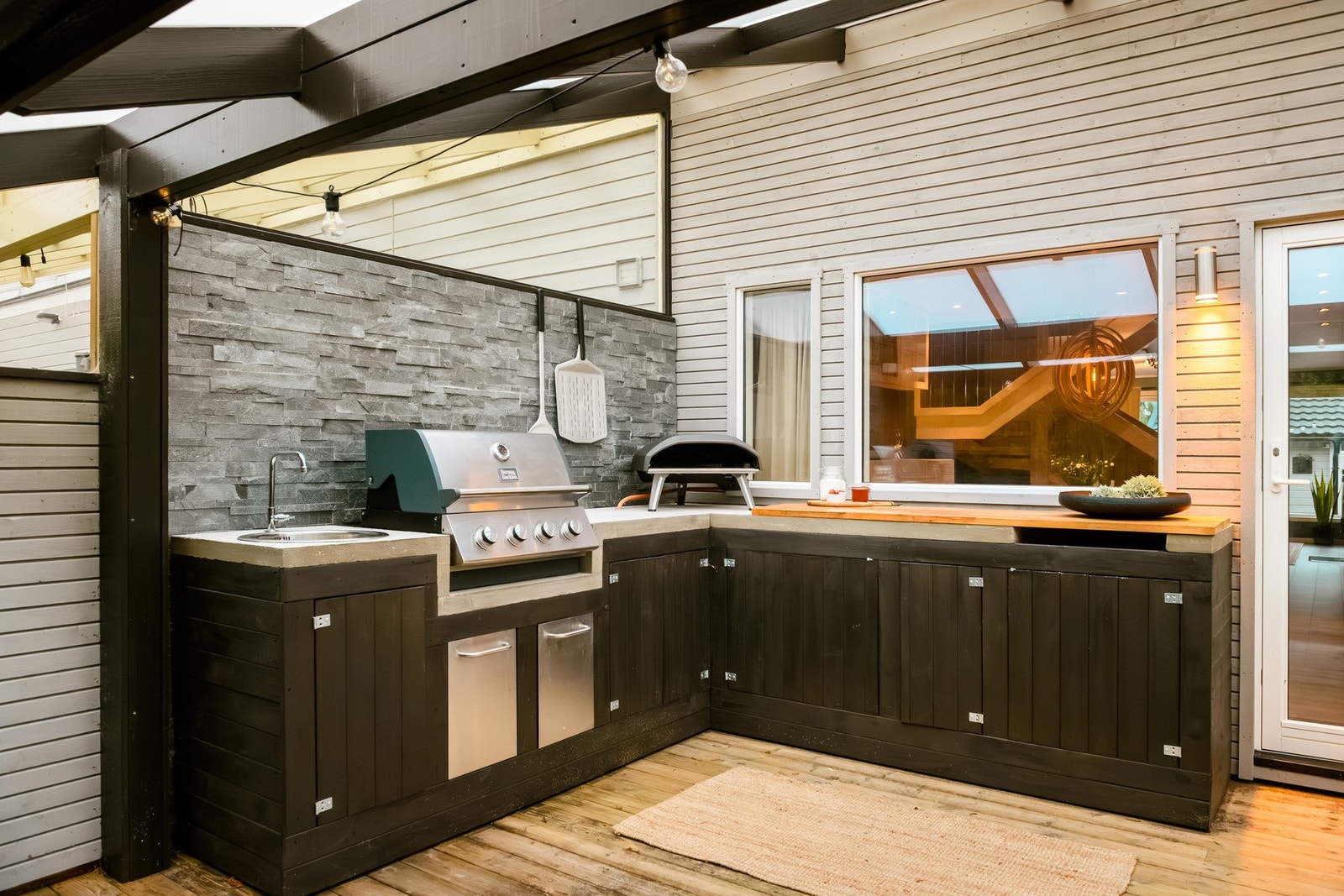 Et skjermet og overbygd uteområde med utekjøkken. Galleribilde