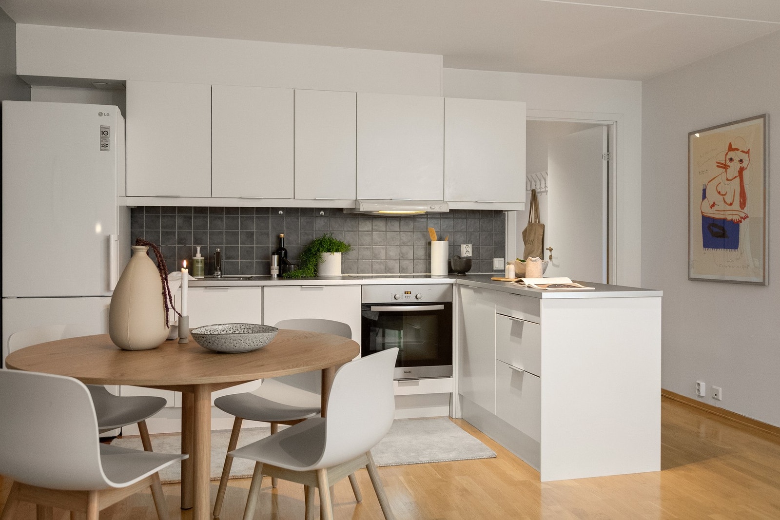 Kjøkkeninnredningen er har hvite glatte fronter, laminat benkeplate med nedfelt kum i rustfritt stål og flisfelt på vegg over kjøkkenbenk. Galleribilde