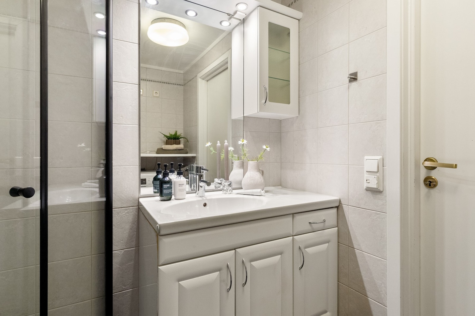 Videre inneholder baderommet servantskap med glatte fronter, heldekkende servant, speil med lysarmatur på vegg, veggmontert klosett, samt dusjhjørne med svingdører fra 2023, hjelpesluk og termostatstyrt blandebatteri. Galleribilde