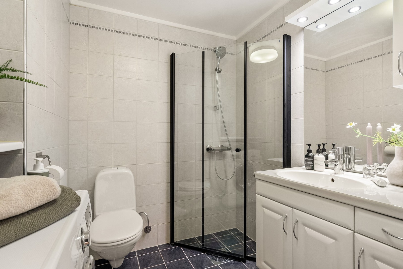 Tidløst flislagt baderom med termometerstyrt gulvvarme, samt opplegg for vaskemaskin og tørketrommel. Galleribilde