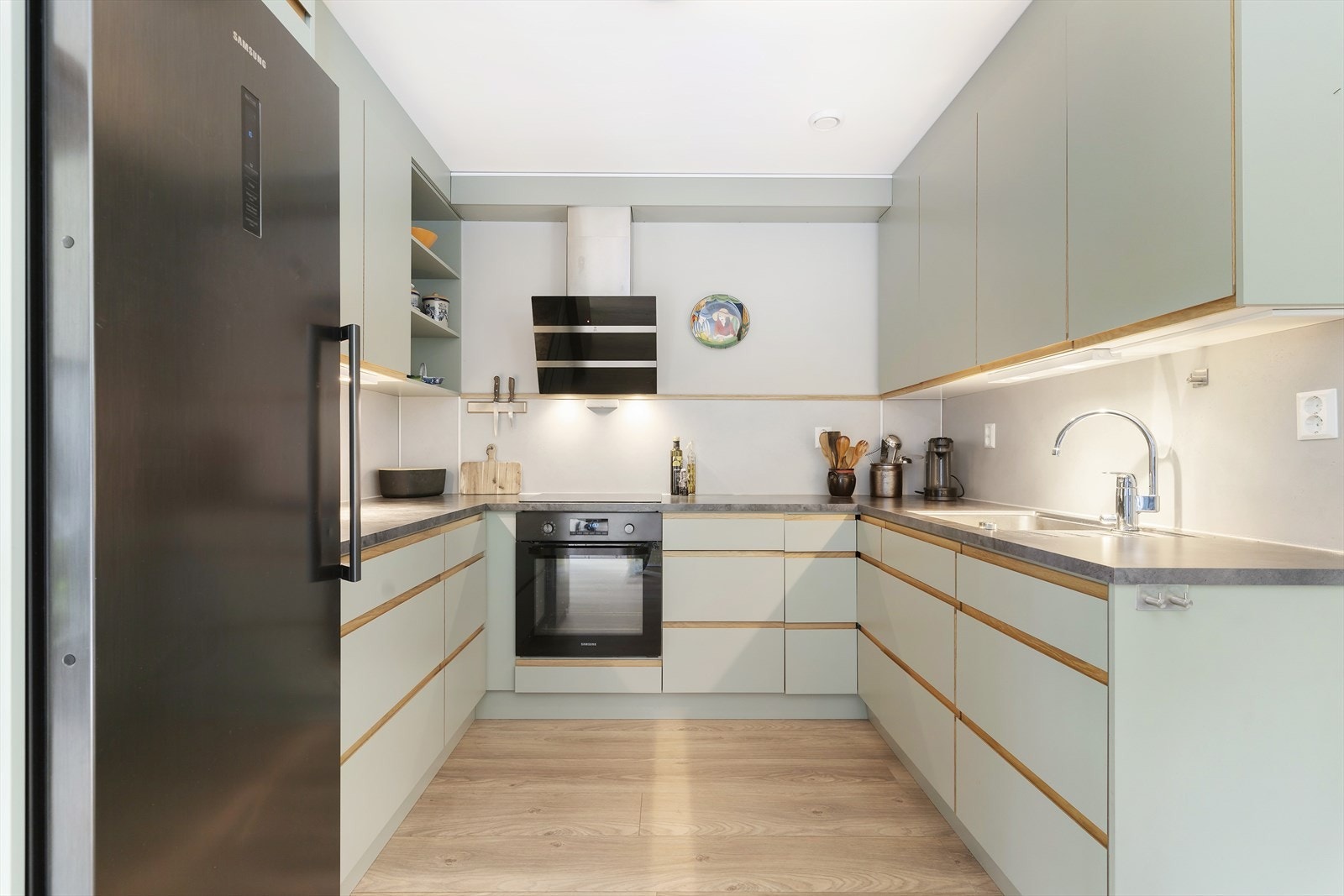 Stilrent kjøkken med delikat grønnfarge. Integrerte hvitevarer, unntatt kjøleskapet. Rikelig med skap og store praktiske skuffer. Innredning fra Nygård Trevare. Galleribilde