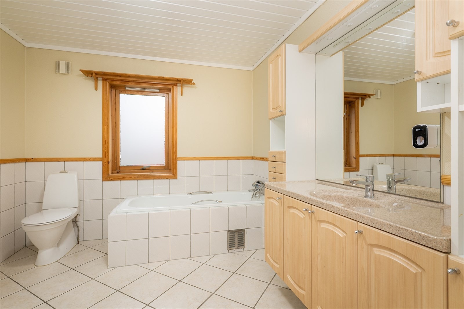 Badet er også innredet med dusjkabinett, innfliset badekar og toalett. På veggoverflatene er den nederste delen flislagt, mens det på resten av veggene er malt strie. Badet har elektrisk vifte i yttervegg. Galleribilde