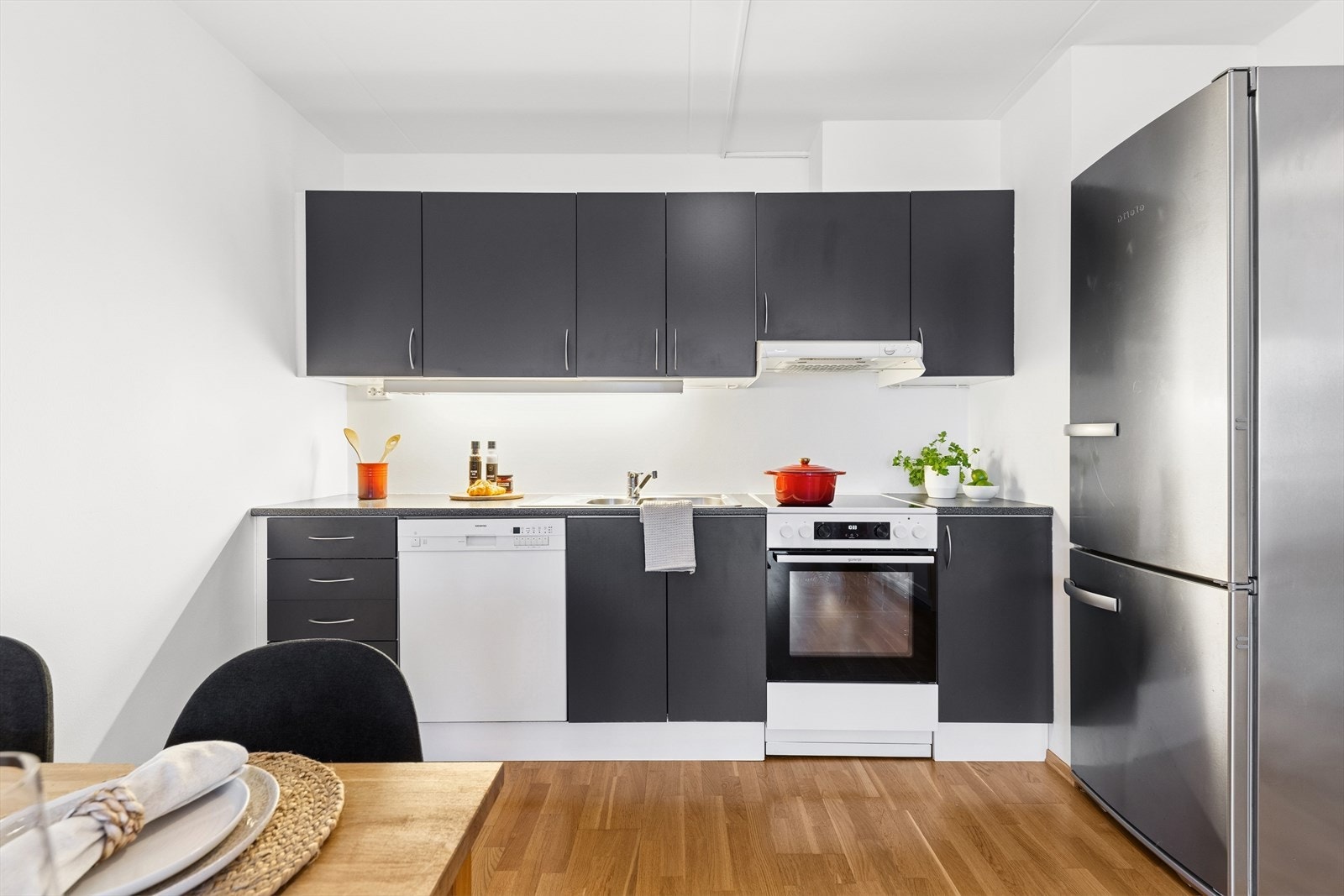 Stilrent kjøkken med frittstående hvitevarer og laminat benkeplate gir et funksjonelt kjøkkenområde. Galleribilde