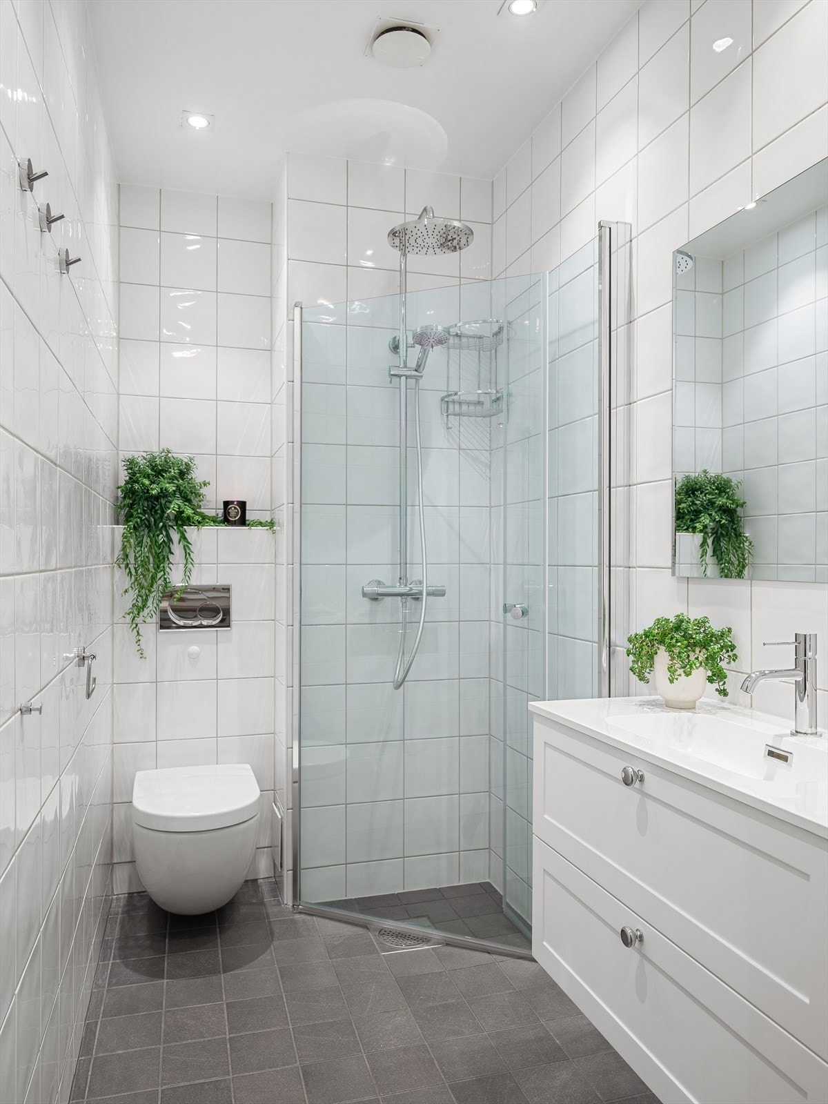 Badet er innredet med dusjnisje med innfellbare glassdører, servant i helstøpt plate og vegghengt toalett. Galleribilde