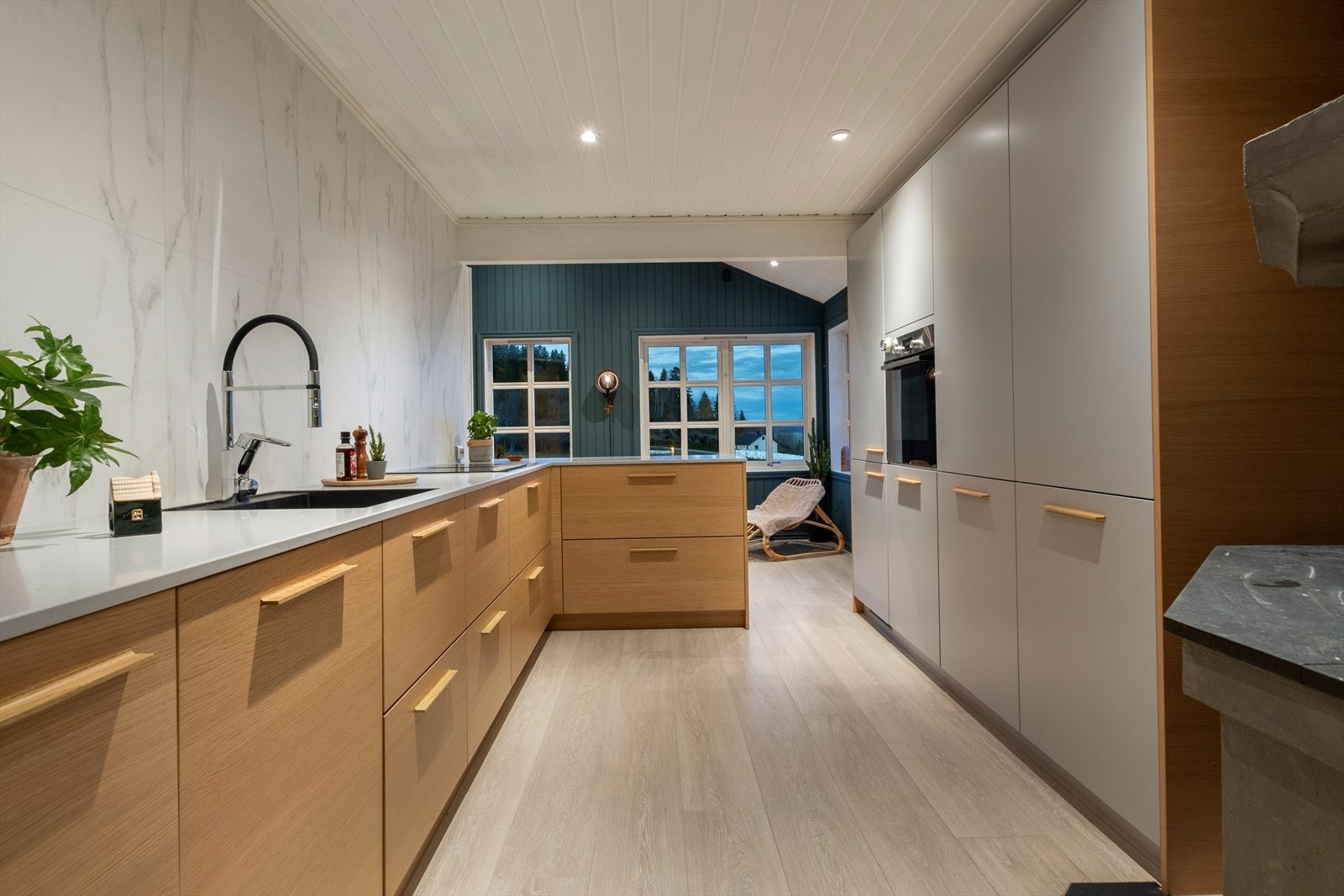 Kjøkken byr på godt med skap- og benkeplass og pene overflater med blant annet baderomsplater på vegg over kjøkkenbenken. Galleribilde