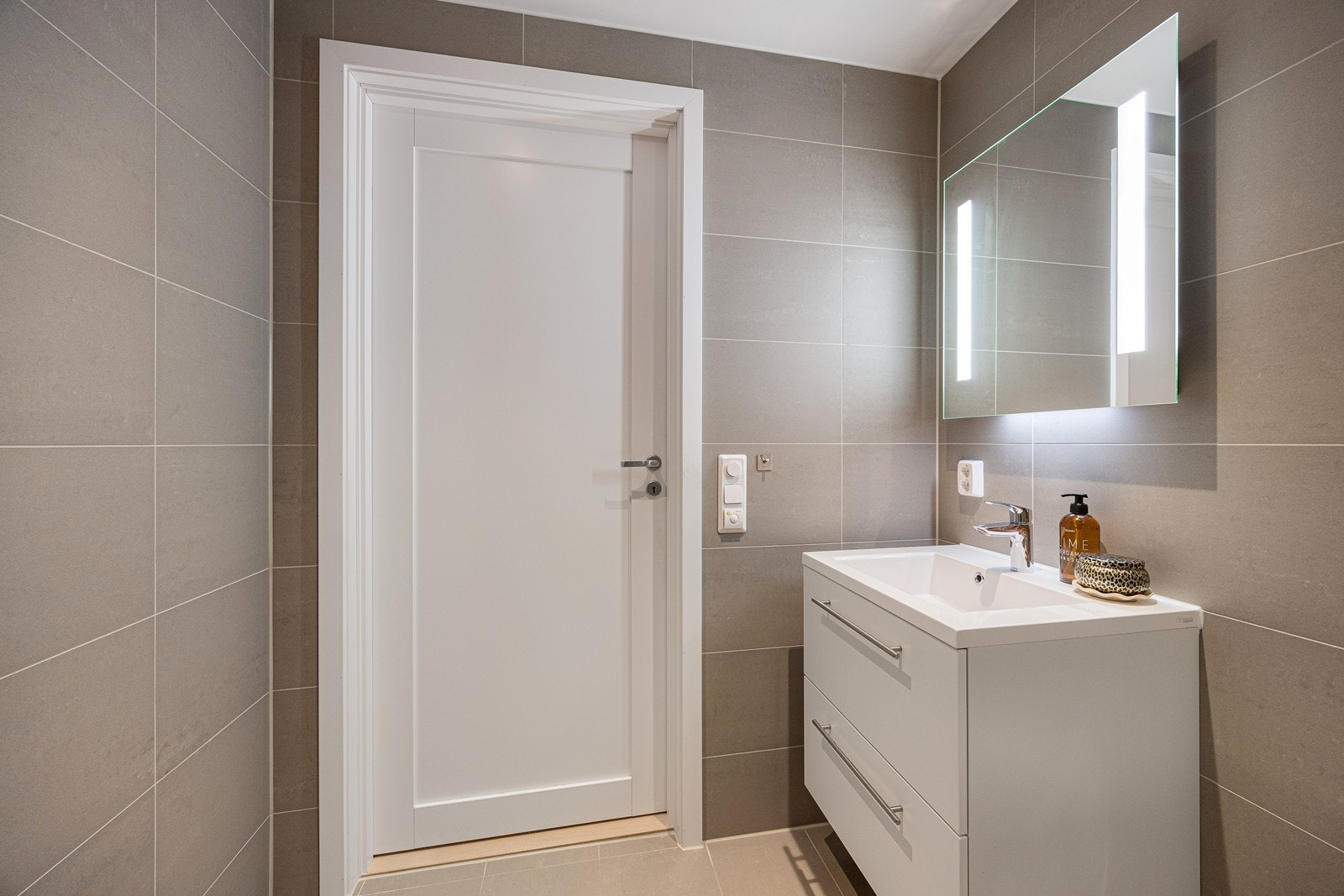 Servant i baderomsmøbel med moderne speil over med integrerte belysning. Galleribilde