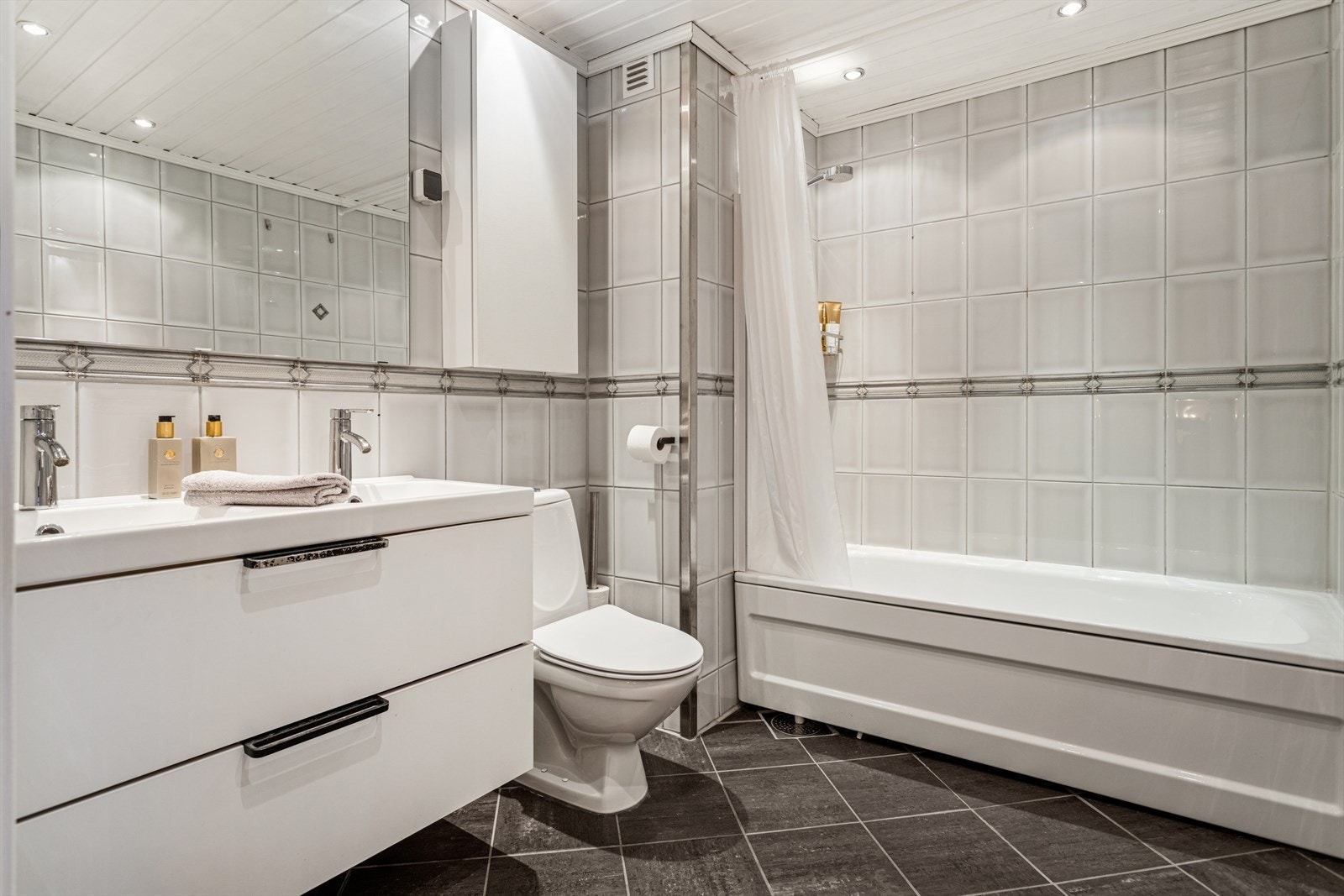 Lyst og romslig flislagt bad med badekar. Galleribilde