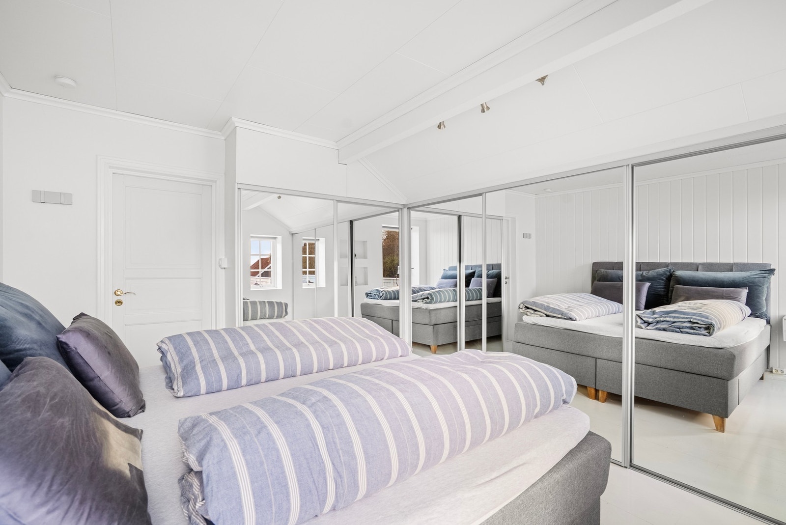 På det største soverommet blir rommets størrelse forsterket av speil i skyvedørsgarderoben Galleribilde