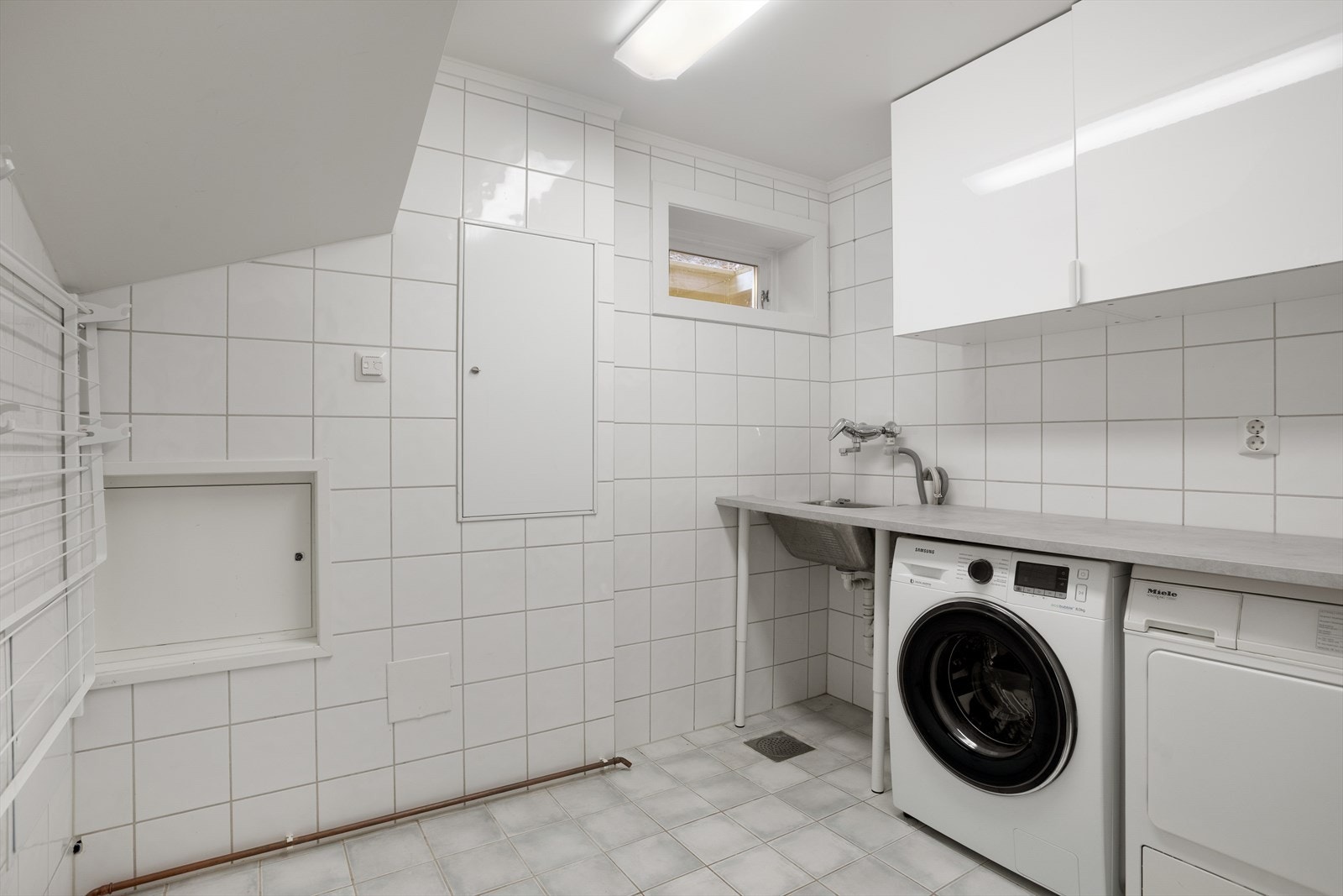 Vaskerommet, også etablert i 2005, er praktisk innredet med flislagte overflater, gulvvarme, benkeplate med vaskekum, skapplass samt opplegg for vaskemaskin og tørketrommel. Her er det også plassert rørfordelerskap, stoppekran, vannmåler og sikringsskap. Galleribilde