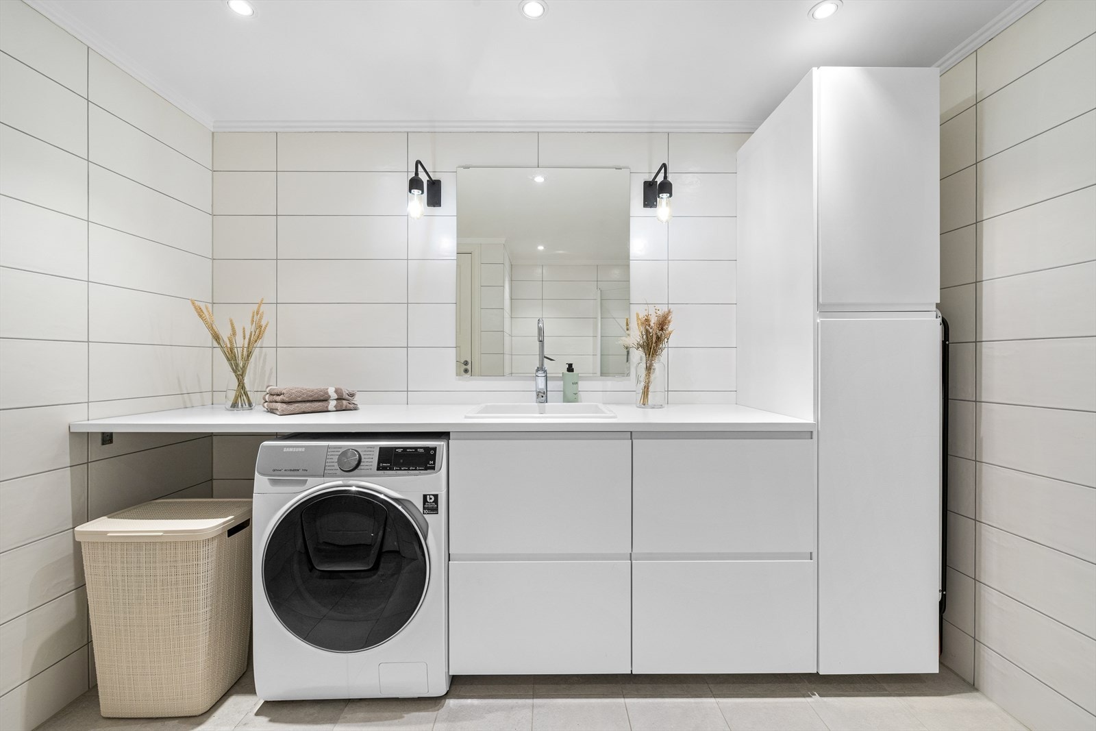 Rommet har også opplegg for vaskemaskin, og det er avsatt plass til det i innredningen. Innredningen består av en benkeplate med oppvaskkum, underskuffer og matchende veggskap. I tillegg har badet toalett samt et dusjhjørne med innfellbare glassvegger. Galleribilde