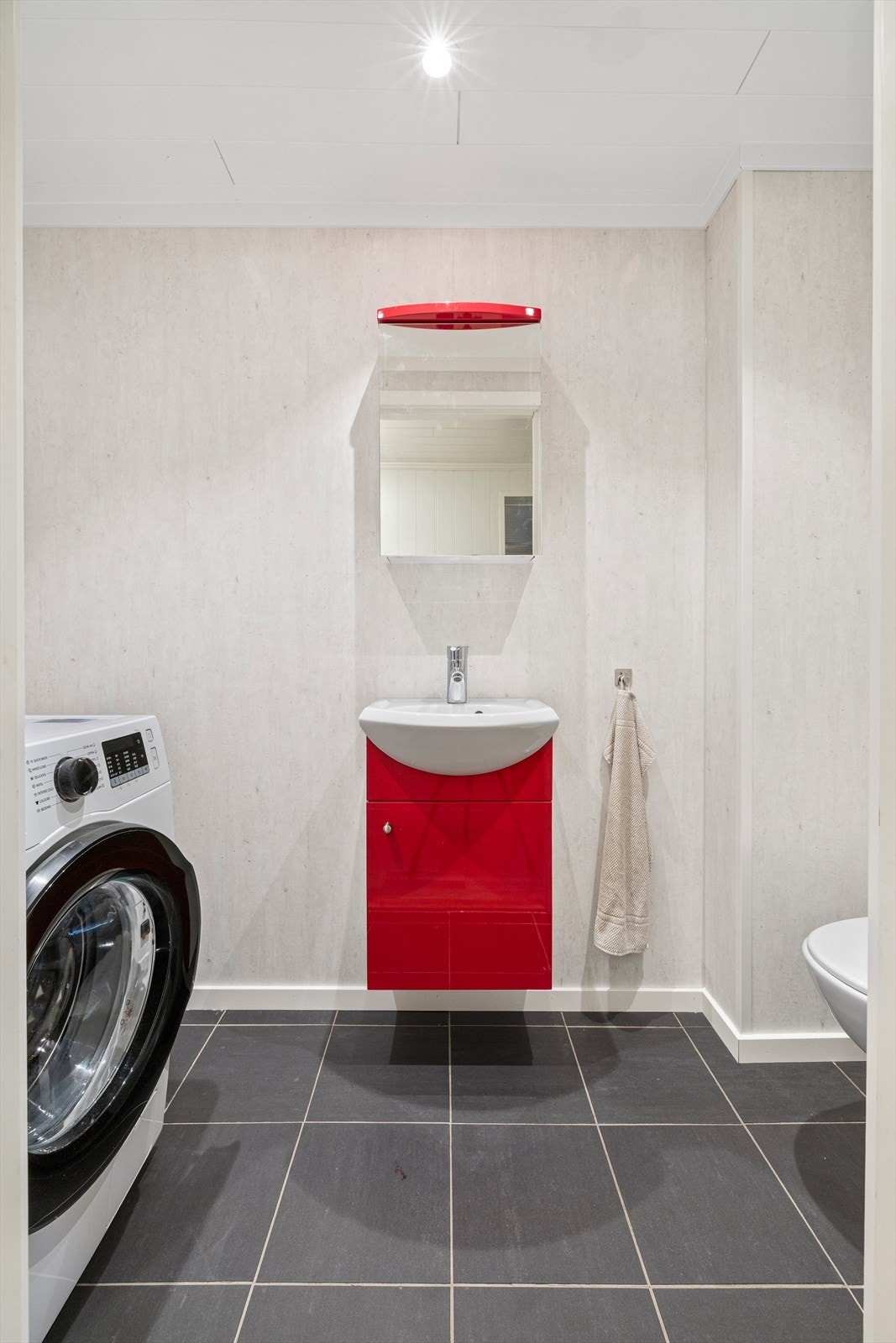 Separat toalettrom / vaskerom med vegghengt toalett, innredning med servant og opplegg til vaskemaskin. Galleribilde