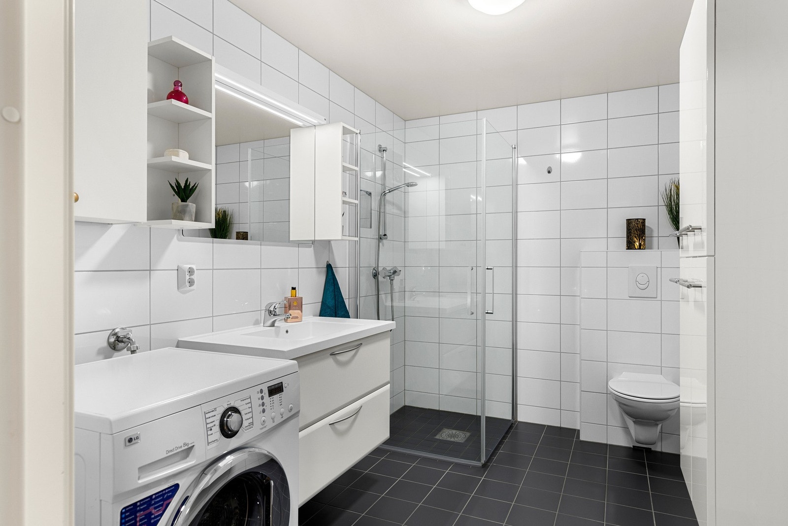 Flislagt bad med dusjhjørne og vegghengt toalett. Galleribilde