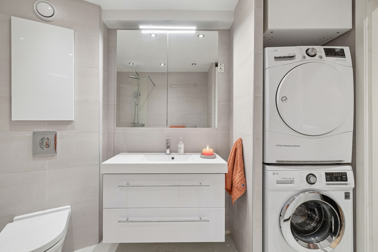 Badet er innredet med vegghengt toalett, servant med innredning med glatte fronter, speilskap og dusjløsning med glassvegg Galleribilde