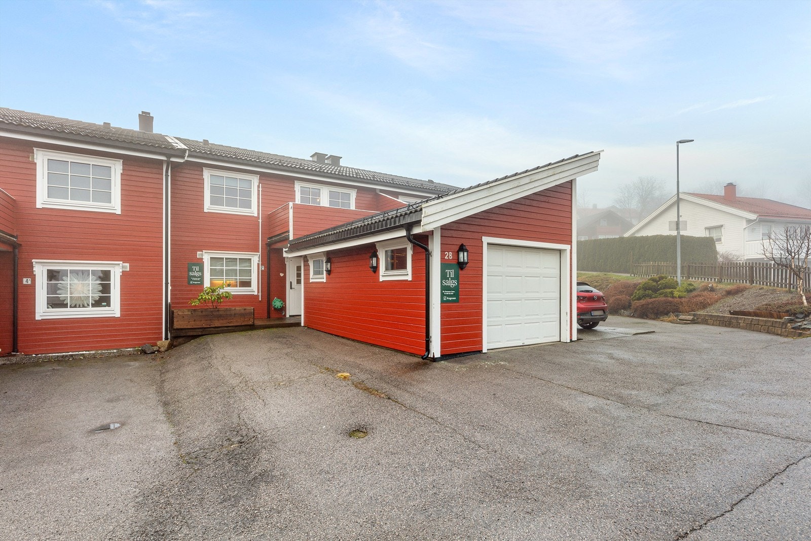 Boligen disponerer en egen garasje med god lagringsplass på hems med stige. Det er inngang til garasjen fra dør under tak ved inngangen. Det følger også en utvendig bod. Parkering i garasje og utenfor egen inngang. Galleribilde