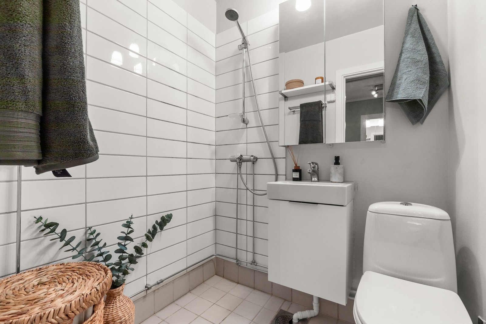 Flislagt bad med dusj, servant med underskap, speilskap med belysning og gulvmontert toalett (nytt i 2025). Galleribilde