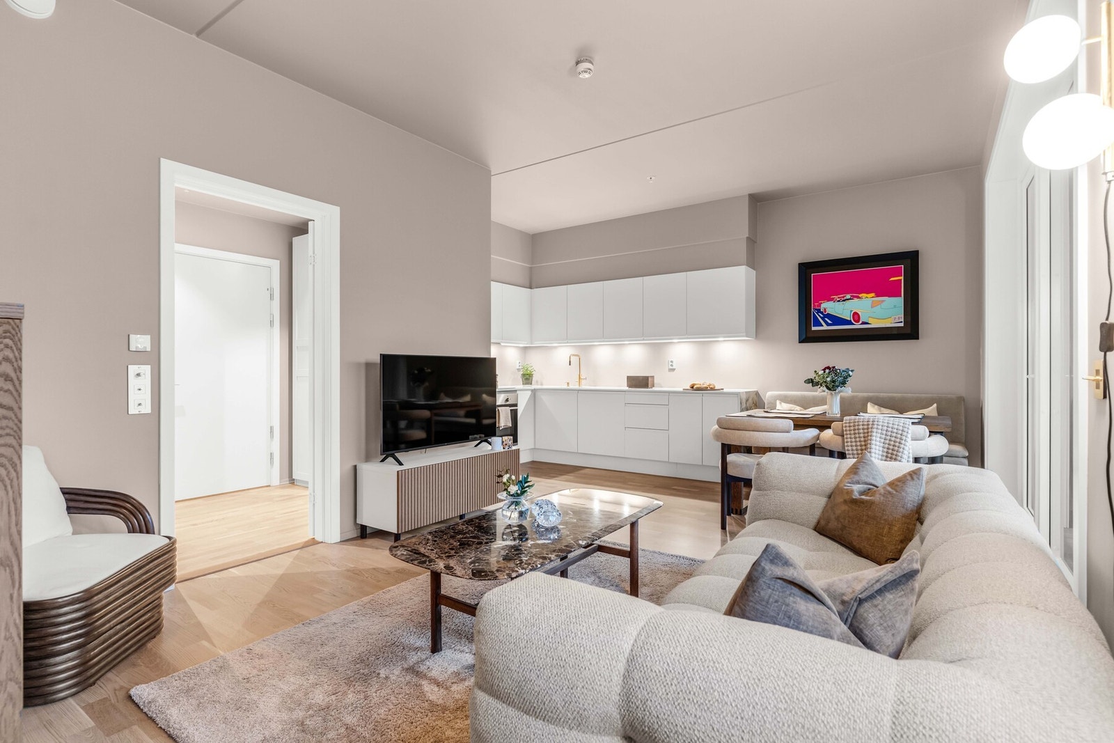 Den åpne løsningen mot kjøkkenet skaper en naturlig flyt mellom sonene og gjør rommet perfekt både for hverdagsliv og sosiale sammenkomster. Galleribilde