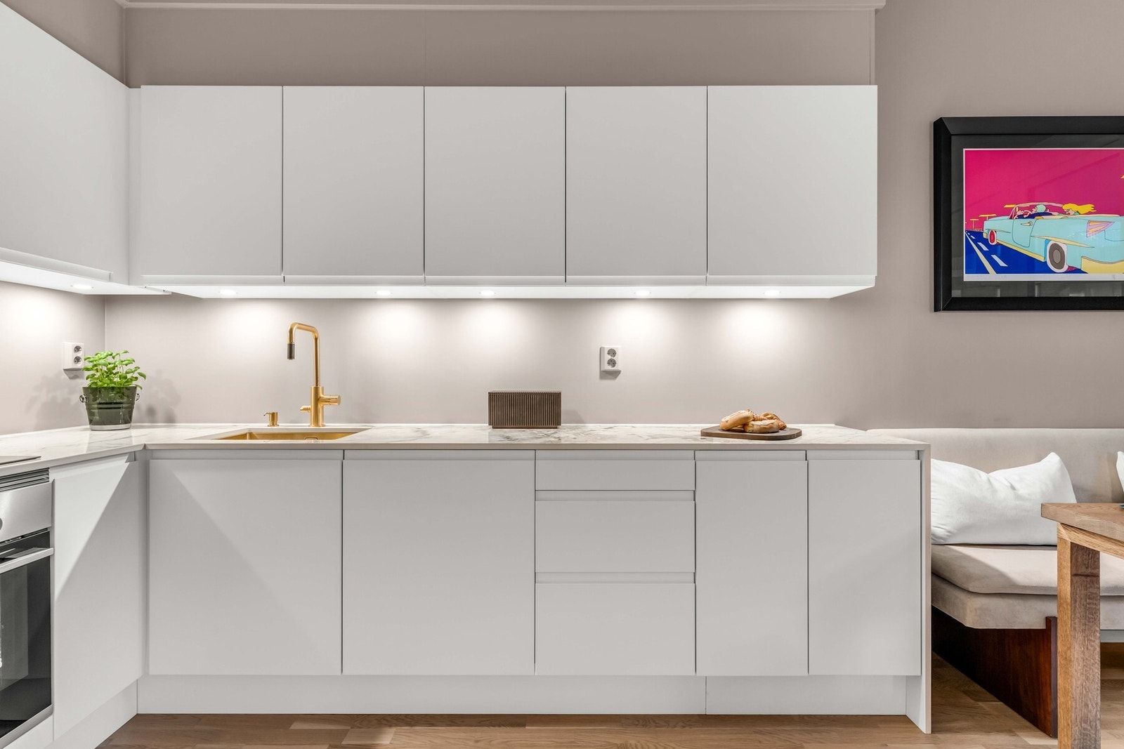 Integrerte hvitevarer gir et helhetlig og minimalistisk uttrykk, mens belysning under overskap tilfører både praktisk arbeidslys og stemning på kveldstid. Galleribilde