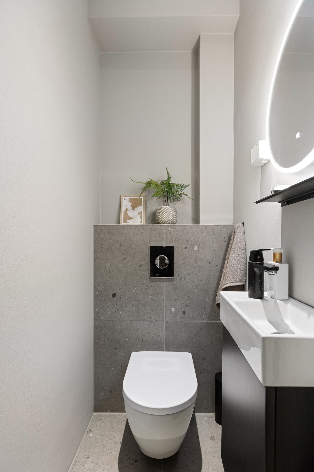 Separat toalettrom med flislagt gulv, vegghengt toalett og servantskap i moderne utførelse. Galleribilde