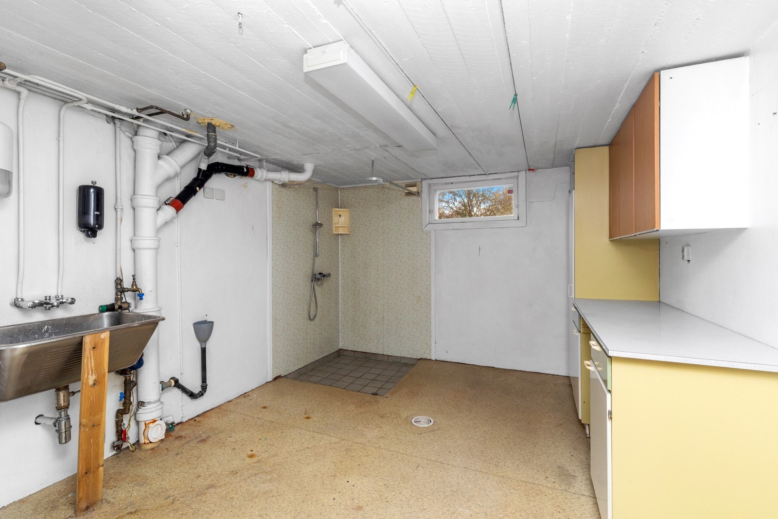 Vaskerom i grovkjeller. Rommet inneholder skyllekar, opplegg til vaskemaskin, dusjhjørne, varmtvannsbereder. Galleribilde