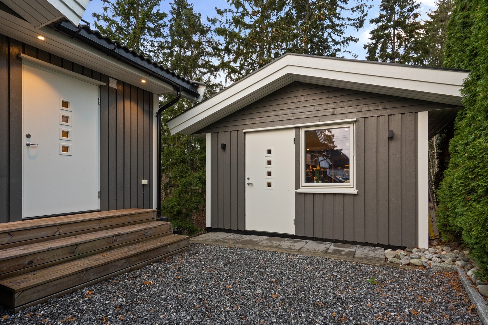 Stående bordkledning pryder fasaden, mens den overflatebehandlede trepanelen gir et moderne preg på boden. Adkomst via en praktisk trapp oppført med impregnerte materialer. Galleribilde