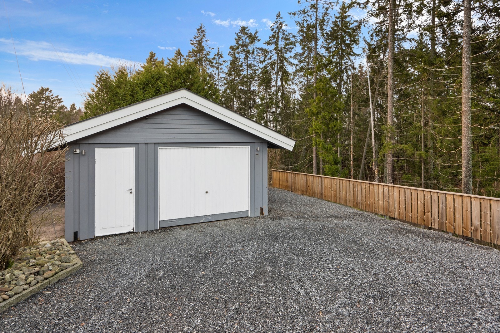 Frittstående garasje med støpt gulv og ringmur av lettklinkerblokker. Fasader kledd i trepanel. Galleribilde