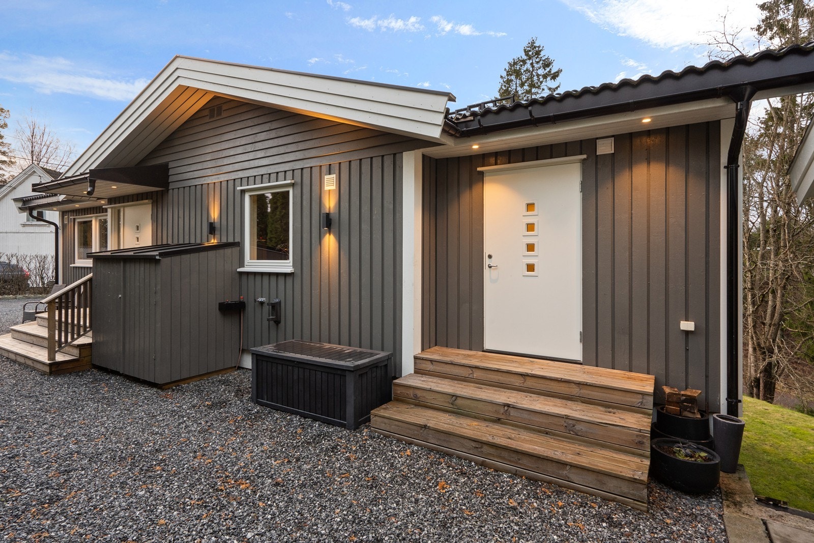 Fasaden har stående bordkledning. Pen belysning på boligen. Galleribilde