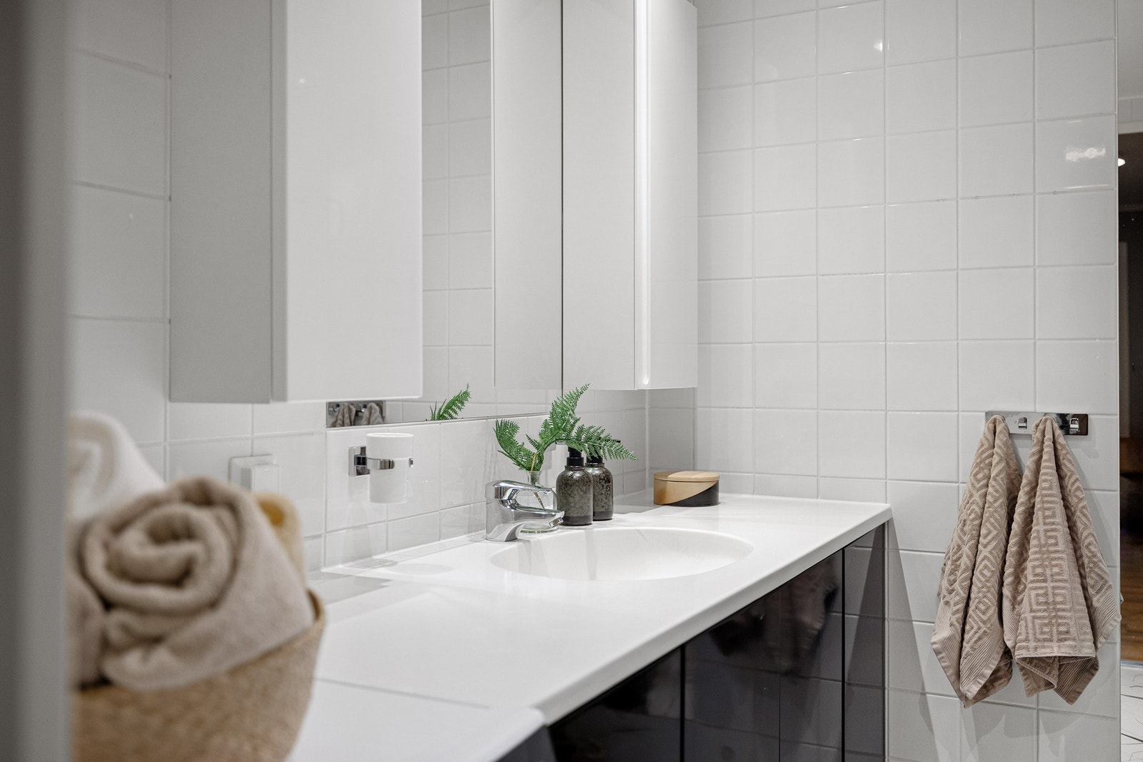 Badet har fliser på gulv og vegger i lyse fargetoner, og det er utstyrt med gulvvarme og downlights Galleribilde